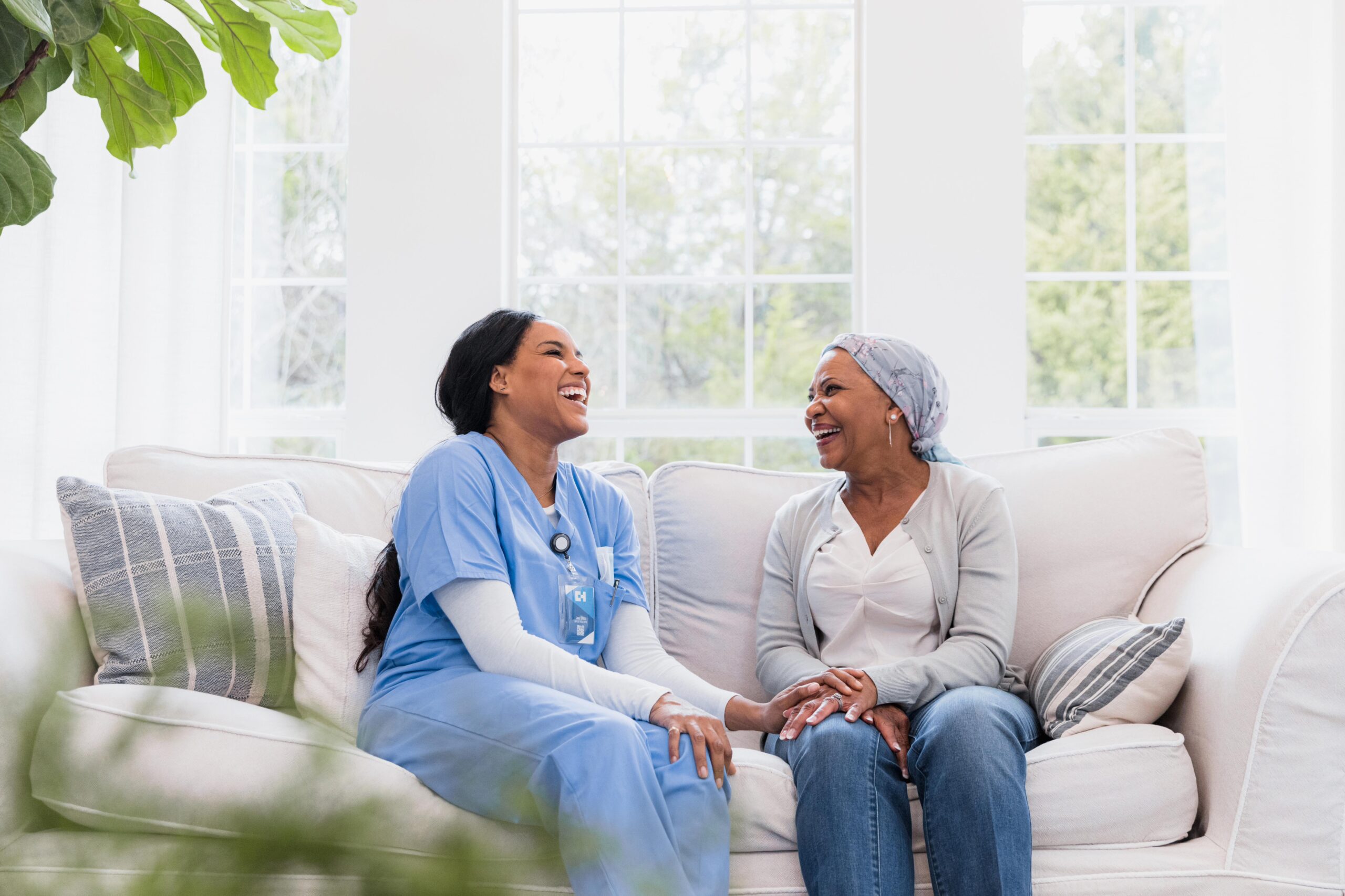 The mid adult female home healthcare nurse and the senior adult female cancer patient share a lighthearted moment together during a home visit.