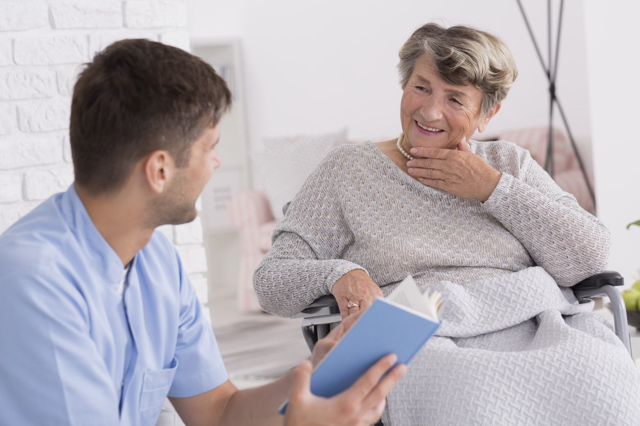 Caregiver reading a book for the elderly lady in retirement home